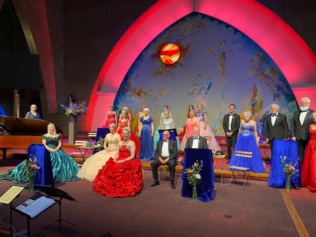 Leden van het operettekoor Wilhelmina in kleurrijke galakleding tijdens het openingsconcert in de Sacramentskerk Breda, mei 2025.