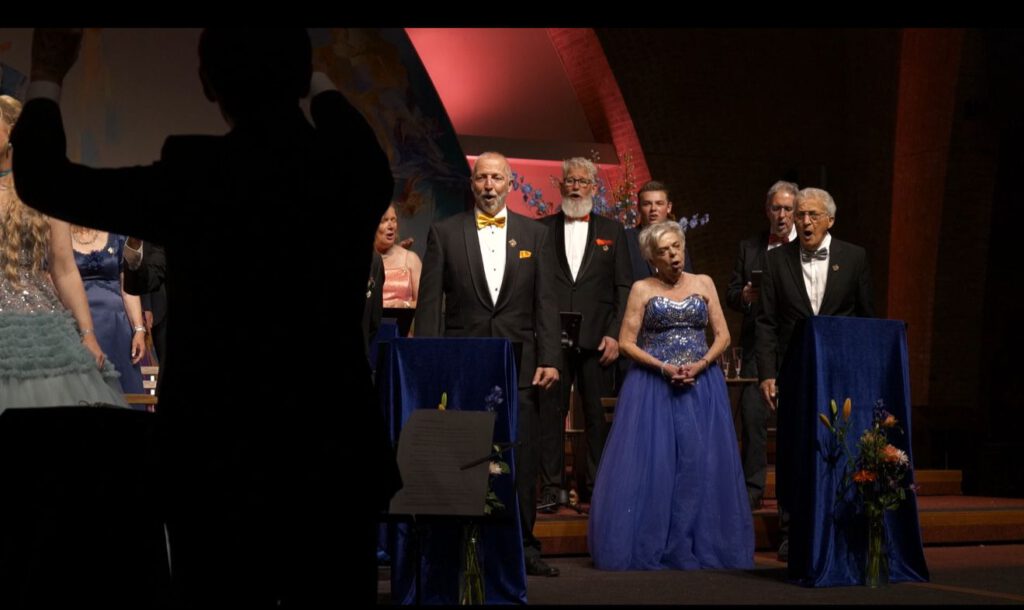 Dirigent leidt koor en solisten tijdens een dramatisch muziekstuk tijdens het openingsconcert in Breda.